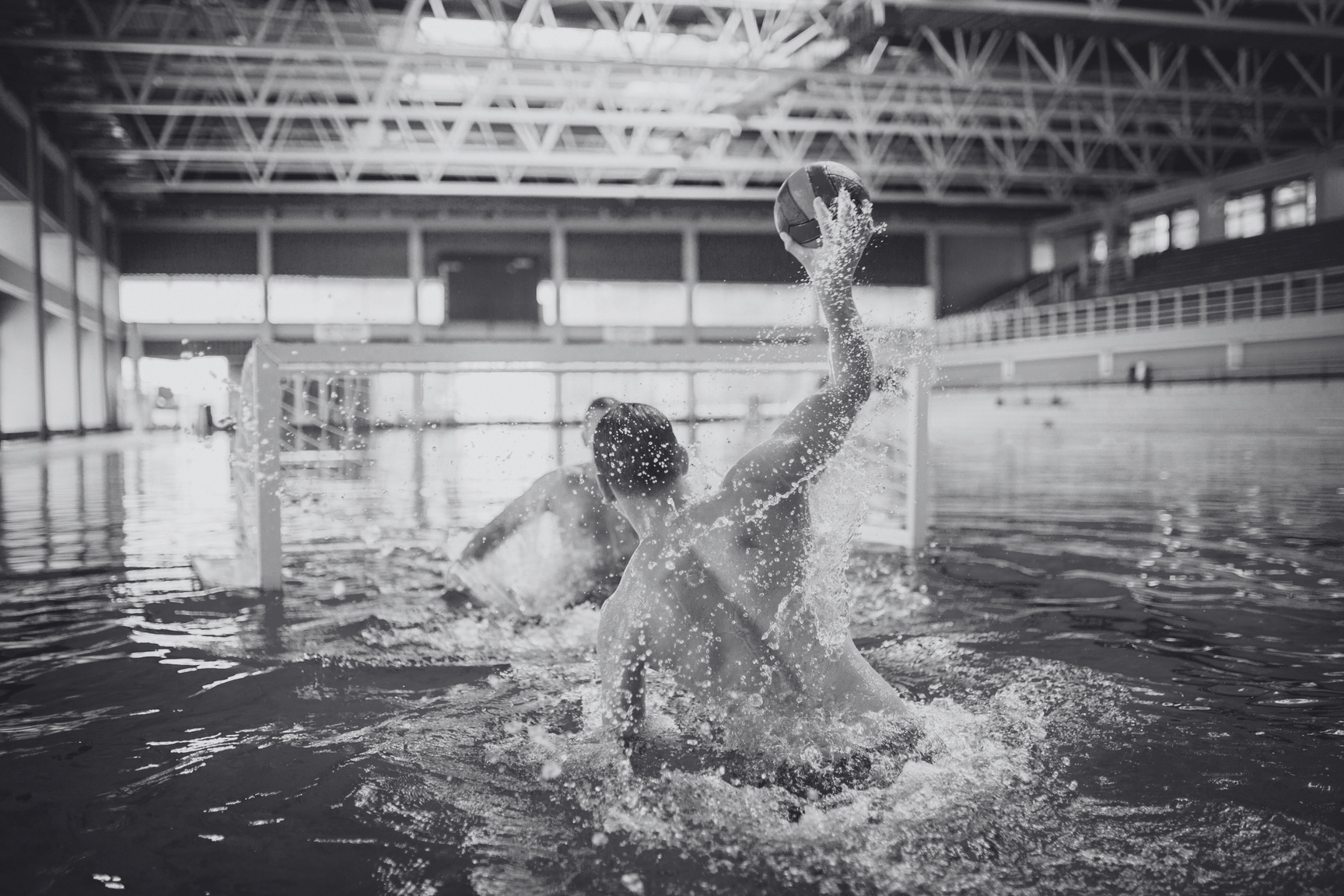 A water polo player rising out of the water to shoot